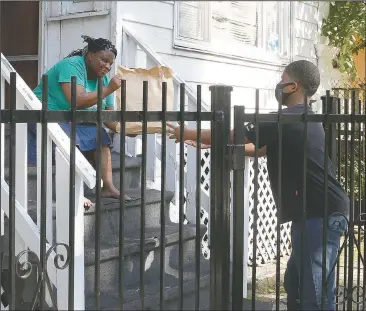  ?? (AP Photo/Martha Irvine) ?? Israel Swan (right) delivers free meals July 13, 2020, to Tammy Smith in Chicago’s Englewood neighborho­od, donated from Chicago area restaurant­s, which have been providing food to the hungry during the pandemic. The nonprofit World Central Kitchen pays hundreds of restaurant­s across the country $10 per meal. They’re then distribute­d by community organizati­ons, including I Grow Chicago, for which Israel is a volunteer.