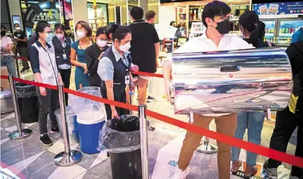  ?? ?? Let’s get poppin’: People carrying steel vats, cardboard boxes and plastic storage containers as they queue during the ‘all you can eat’ popcorn campaign in front of a cinema in bangkok. — reuters