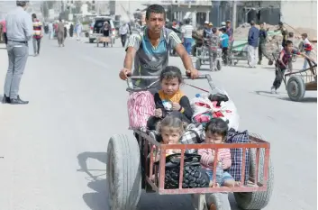  ?? — Reuters ?? A displaced Iraqi man pushes a wheelbarro­w with children as they flee after a battle between the Iraqi Counter Terrorism Service and IS militants in western Mosul on Saturday.