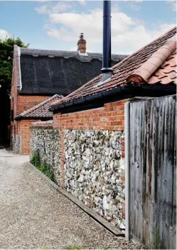  ??  ?? THIS PAGE, ABOVE The barn is part of a series of mid-19th-century red-brick-and-flint farm buildings and would once have served as a byre for cattle LEFT Cara has displayed her favourite
peonies in an old ceramic pot on the kitchen table OPPOSITE White painted floorboard­s and steep ceilings reflect light into the kitchen and utility room. The antique pine larder was a Gumtree find