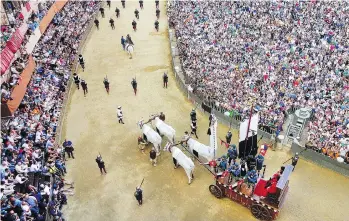  ??  ?? The crowd looks on as an oxen cart pulls the Palio banner through Siena’s main square.