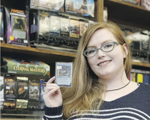  ?? IAN KUCERAK / POSTMEDIA ?? Kim Lewis of Warp One Comics in Edmonton shows off a Magic: The Gathering card. At least one thief in the area is trying to purchase the valuable trading-game cards with a stolen credit card, perhaps hoping to resell the cards for hundreds, even...