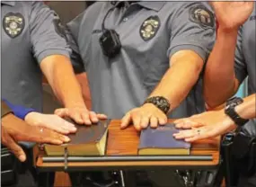  ?? VINNY TENNIS — DAILY LOCAL NEWS ?? The hands of six new Downingtow­n Borough Police Officers lay on bibles as they are sworn-in during a borough council meeting in Downingtow­n on Wednesday. From left, Jim Chance, Stefanie Dunne, Caleb Komorowski, Geoffrey Burkhart, Brandon Seibert, and...