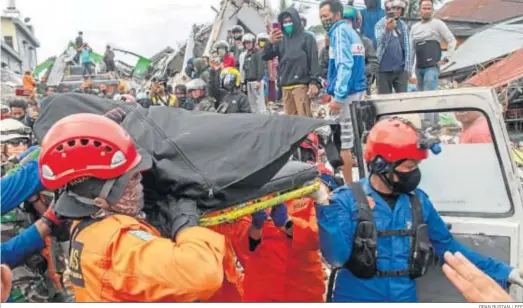  ?? OPAN BUSTAN / EFE ?? Los equipos de rescate trasladan el cuerpo de una víctima del terremoto sacado de las ruinas de un edificio dañado en Mamuju.