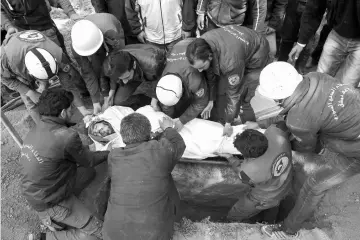  ??  ?? Syrian civil defence volunteers, known as the White Helmets, bury the body of one of their comrades killed in an air strike on the rebelheld village of Mohammadiy­ah during his funeral procession in Kafr Batna in the eastern Ghouta area, on the...