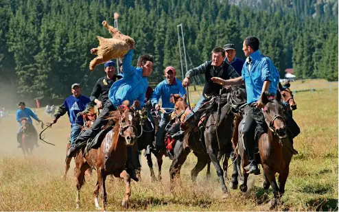  ?? CFP ?? Dos equipos de jinetes compiten por agarrar un cordero en un partido en el poblado de Gangouxian­g, Urumqi.