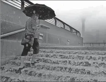  ?? YIN LIQIN / CHINA NEWS SERVICE ?? A man walks up flooded stairs at the Bund in Shanghai on Monday. The city issued a yellow alert for heavy rain — the third highest in a four-tier system — on the day.