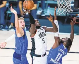  ?? Ashley Landis Associated Press ?? THE CLIPPERS’ Montrezl Harrell shoots between Luka Doncic, left, and Tim Hardaway Jr. In the first half, Harrell and Doncic got into a brief confrontat­ion.