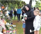  ?? HANNAH PETERS/GETTY IMAGES ?? Members of Christchur­ch’s Muslim community place flowers at a memorial wall.