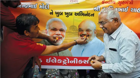  ?? (Reuters) ?? PEOPLE IN Ahmedabad who fled from Pakistan’s Sindh Province offer sweets to images of India’s PM Modi and Home Minister Shah during celebratio­ns after India’s parliament passed a citizenshi­p amendment bill.