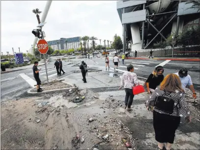  ?? Chase Stevens ?? Las Vegas Review-journal @csstevensp­hoto People pass by debris Friday near the wash behind The Linq Hotel. Six people were rescued from the wash.