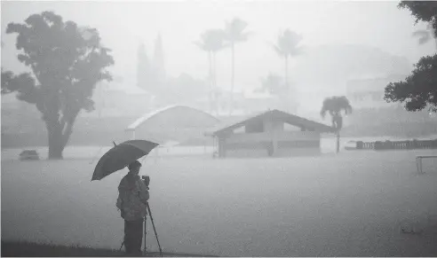  ?? MARIO TAMA / GETTY IMAGES ?? A man takes photos of floodwater­s from Hurricane Lane rainfall on the Big Island Thursday in Hilo, Hawaii. Hurricane Lane has brought more than a foot of rain to some parts of the Big Island and tropical storm conditions were expected late Thursday.