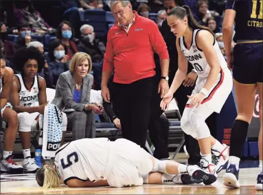  ?? Jessica Hill / Associated Press ?? UConn’s Paige Bueckers lies on the ground after injuring her knee as Nika Mühl and head coach Geno Auriemma look on the second half against Notre Dame on Sunday.