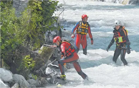  ?? FOTO: LENNART PREISS/DPA ?? Einsatzkrä­fte der Wasserwach­t suchen nahe der Höllentalk­lamm den Hammersbac­h und den Uferbereic­h nach Vermissten ab. Am Vortag war nach starken Regenfälle­n eine Flutwelle durch die Schlucht gerauscht. Sie riss mehrere Menschen mit sich.