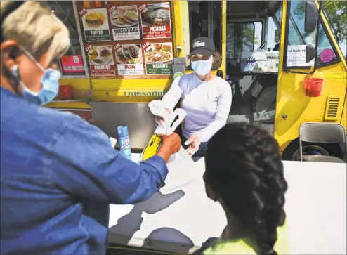  ?? Brian A. Pounds / Hearst Connecticu­t Media ?? Andrea Figueroa, of West Haven, waits on customers at the Tacos Los Michoacano­s food truck at Long Wharf in New Haven late last month. The trucks were forced to close when the coronaviru­s pandemic hit to address health department concerns including the use of masks and social distancing.
