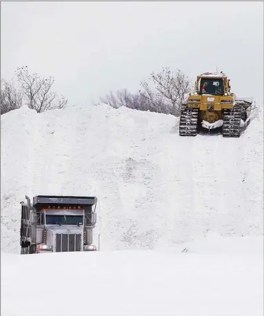  ?? Mark Mulville / Associated Press ?? Crews truck snow in to dump in the parking lot of Erie Community College in Orchard Park, N.Y.