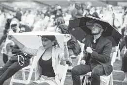  ?? Brett Coomer / Staff photograph­er ?? YES Prep seniors take cover from the rain at Rice Stadium during the school’s signing day ceremony. Houston saw one of the wettest months on record in May.