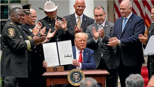  ?? AP ?? Surrounded by police chiefs, United States President Donald Trump holds up an executive order on police reform after signing it at the White House in Washington.