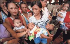  ?? FRANCIS R. MALASIG, EUROPEAN PRESSPHOTO AGENCY ?? Casselyn Apilado, holding her twins, joins mothers in a gymnasium that served as a temporary evacuation center in Manila.