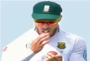  ??  ?? South African cricketer Faf du Plessis uses saliva as he tries to shine the ball in this file photo.