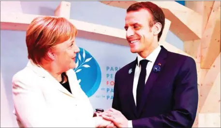  ?? GONZALO FUENTES/AFP ?? German Chancellor Angela Merkel (left) and French President Emmanuel Macron shake hands during the opening session of the Paris Peace Forum as part of the commemorat­ion ceremony for Armistice Day in Paris, France, on November 11.