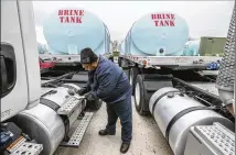  ?? JOHN SPINK / JSPINK@AJC.COM ?? Jason Robinson logs data Thursday as he prepares brine trucks for the state Department of Transporta­tion. Brine is a salt water mix that helps prevent ice from forming