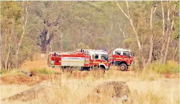  ??  ?? Fire trucks sit in a valley awaiting instructio­ns as a fire burns on a ridge, driven by strong winds in the suburb of Brigadoon in Perth.