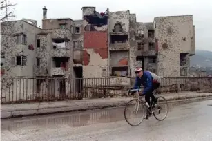  ?? (AFP/Getty) ?? A cyclist rides past destroyed building in Mostar, 18 December 1995