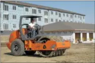  ??  ?? Pete Kelsch waits for a grader to pass by at an apartment constructi­on site in northeast Bismarck, N.D.