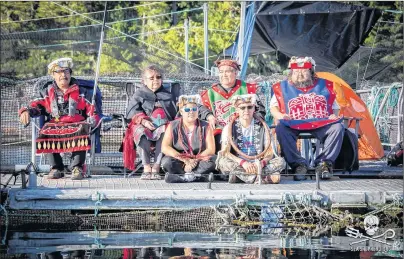  ?? CP PHOTO/HO-FACEBOOK-SWANSON OCCUPATION ?? Protesters gather at the Marine Harvest fish farm on Swanson Island, near Alert Bay, B.C., in a handout photo from the Facebook page Swanson Occupation. Ernest Alfred, 36, sitting cross-legged on the right wearing a cedar bark neck ring, sits with...