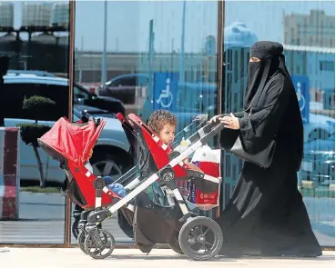  ?? /Reuters ?? Driving change: A Saudi woman pushes a stroller carrying her children in Riyadh. The lifting of the ban on women drivers is set to boost the workforce in the country, which is under pressure from lower oil prices.