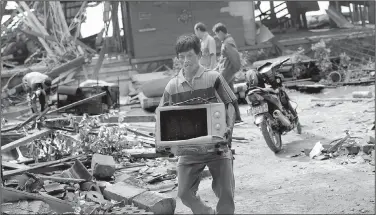  ?? AP/TATAN SYUFLANA ?? A man salvages an item during cleanup Monday from Saturday’s tsunami in Indonesia. Doctors treated injured victims while hundreds of military members and volunteers scoured debris-strewn beaches for survivors.