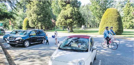  ?? DARREN STONE, TIMES COLONIST ?? Cyclists ride past cars in a parking lot on Circle Drive in Beacon Hill Park on Thursday. The new parking arrangemen­t takes effect Saturday and will continue through the summer.