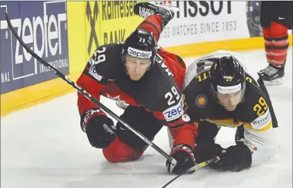  ?? The Associated Press ?? Canada forward Nathan MacKinnon, left, and Germany’s Leon Draisaitl crash to the ice while battling during their IIHF World Championsh­ip quarterfin­al in Cologne, Germany, on Thursday. Canada won 2-1.