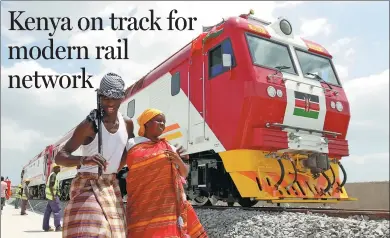  ?? XING YIHANG/ FOR CHINA DAILY ?? Locals stand beside one of the six China-made locomotive­s at the Port Reitz in Mombasa, Kenya. The country’s first modern railway line is near completion.