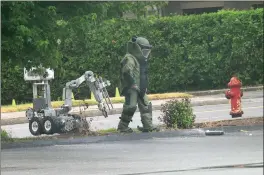  ?? Ernest A. Brown photo ?? A member of the R.I. State Bomb Squad inspects a suspicious package after it was exploded just after 2 p.m. Thursday on Cumberland Street in Woonsocket.