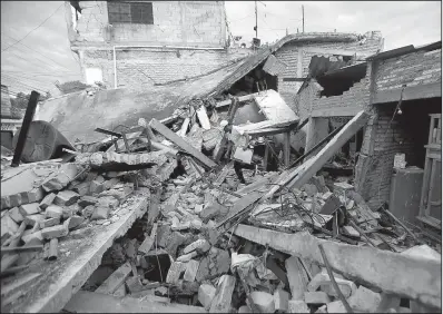  ?? AP/EDUARDO VERDUGO ?? A resident on Wednesday crosses a pile of rubble caused by Tuesday’s 7.1 earthquake, in Jojutla, Morelos state, Mexico.