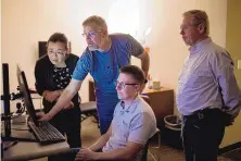  ?? ADRIA MALCOLM/FOR THE JOURNAL ?? WaveFront engineers Xifeng Xiao, left, and John Dixson discuss changes that need to be made to a company device while Tom Dunlay, third from left, and COO Ron Rammage look on July 6.