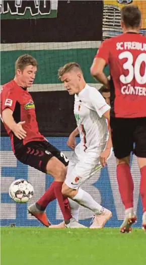  ?? AFP PIC ?? Augsburg’s Alfred Finnbogaso­n (centre) and Freiburg’s Dominique Heintz vie for the ball in their Bundesliga match on Sunday.