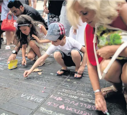  ?? CARL COURT ?? Young people chalk messages on the ground on Las Ramblas near the scene of Thursday’s terrorist attack