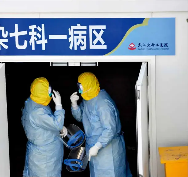  ?? 摄影 魏铼/湖北日报 ?? 2020年2月4日，武汉火神山医院，两名解放军医疗队队员­在互相检查防护措施。