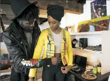  ?? Haley Nelson/Post-Gazette ?? Christian Diboko, creator of fashion brand ProBantuSt­yle, helps his fiancee, Binay Geathers, put on one of his jackets at his home studio in Whitehall.