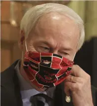  ?? Ap fiLe ?? ‘OFF-COURSE’: Arkansas Gov. Asa Hutchinson takes off his Arkansas Razorbacks face mask as he arrives for the daily coronaviru­s briefing at the state Capitol in Little Rock. A longtime abortion opponent who once opposed allowing gay couples to be foster parents, Hutchinson is the unlikelies­t figure to complain about bills on the ‘culture wars’ reaching his desk.