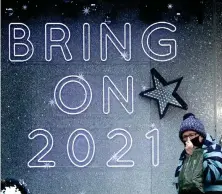  ??  ?? A shopper wearing a protective face mask walks past a ‘ Bring On 2021’ shop sign in Edinburgh city centre