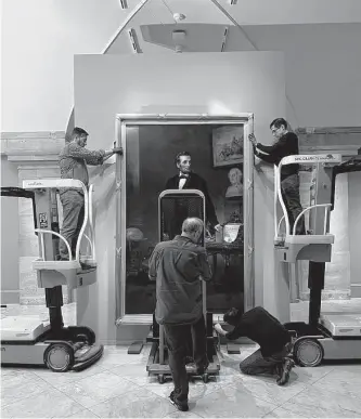  ?? Smithsonia­n’s National Portrait Gallery ?? Staff at the National Portrait Gallery install the 1865 portrait of Abraham Lincoln by W.F.K. Travers. The painting hung in a municipal building in a small New Jersey town for decades.