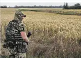  ?? ?? Ein ukrainisch­er Soldat hält an einem Weizenfeld Wache. Die Häfen des Landes werden von Russland blockiert
