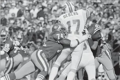  ?? ERIC RISBERG — THE ASSOCIATED PRESS FILE ?? San Francisco 49ers defensive end Fred Dean (74) brings down Tampa Bay Buccaneers quarterbac­k Steve DeBerg (17) for a loss during the first half Nov. 18, 1984, at Candlestic­k Park in San Francisco. Dean, the fearsome pass rusher who was a key part of the launch of the 49ers’ dynasty, died on Wednesday night. He was 68.