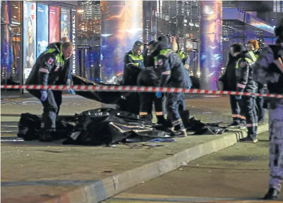  ?? VASILY PRUDNIKOV/EFE ?? Bomberos y policías, con algunos cadáveres a las puertas del auditorio donde se produjo la matanza.