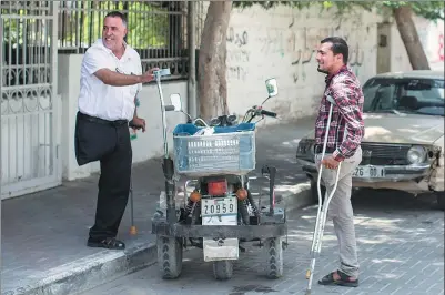  ?? MAHMUD HAMS / AGENCE FRANCE-PRESSE ?? Imad al-Firi (left), who was wounded during the 50-day war between Israel and Hamas in the summer of 2014, talks to a fellow amputee outside Gaza’s Artificial Limbs and Polio Centre in Gaza last month..