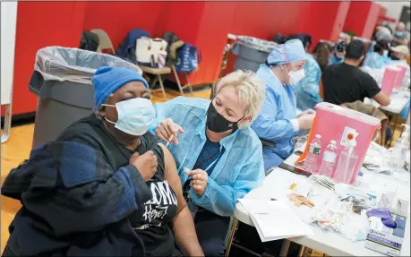  ?? SETH WENIG — THE ASSOCIATED PRESS ?? Mary Jenkins, left, received the COVID-19vaccine in Paterson, N.J. Jan. 21. The first people arrived around 2:30a.m. for the chance to be vaccinated at one of the few sites that does not require an appointmen­t. Smaller-than-expected vaccine deliveries from the federal government have caused frustratio­n and confusion and limited states’ ability to attack the outbreak that has killed over 400,000America­ns.